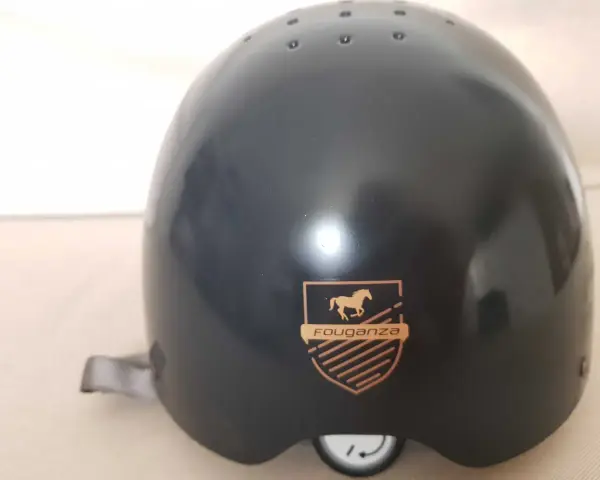 Czarny kask jeździecki Fouganza z logo konia i tarczą.
