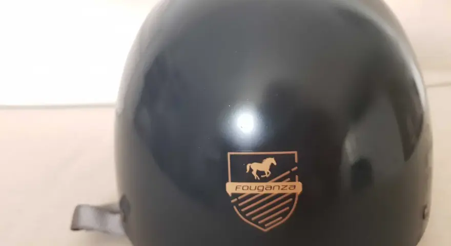 Czarny kask jeździecki Fouganza z logo konia i tarczą.